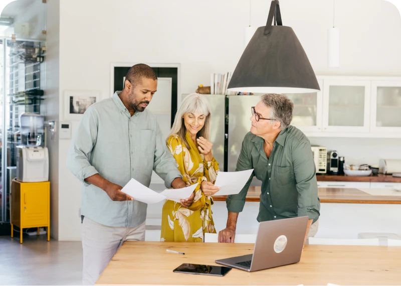 Team reviewing papers near laptop